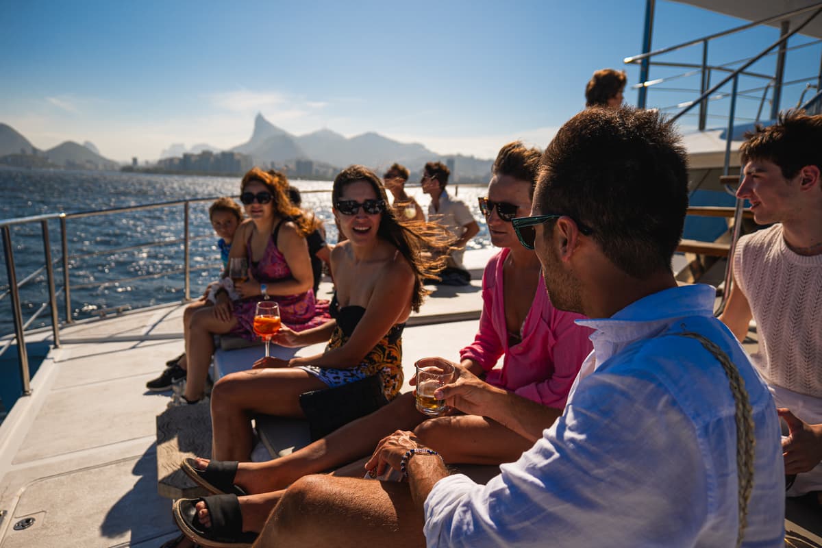 Grupo relaxando no deck do barco com o Cristo Redentor ao fundo